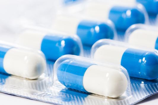 Cápsulas de antibiótico en blíster, representando el uso común de estos medicamentos y la necesidad de complementar con probióticos como Pisalak.